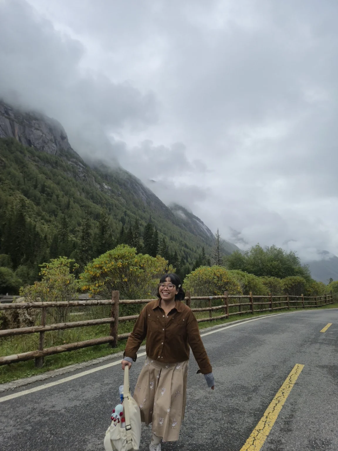 Mazwani smiling on a mountain road surrounded by mist and lush forest