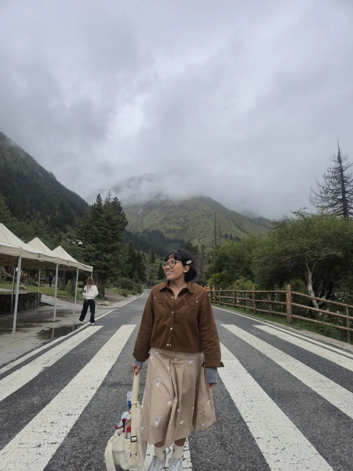 Mazwani looking to the side on a scenic road with misty mountains